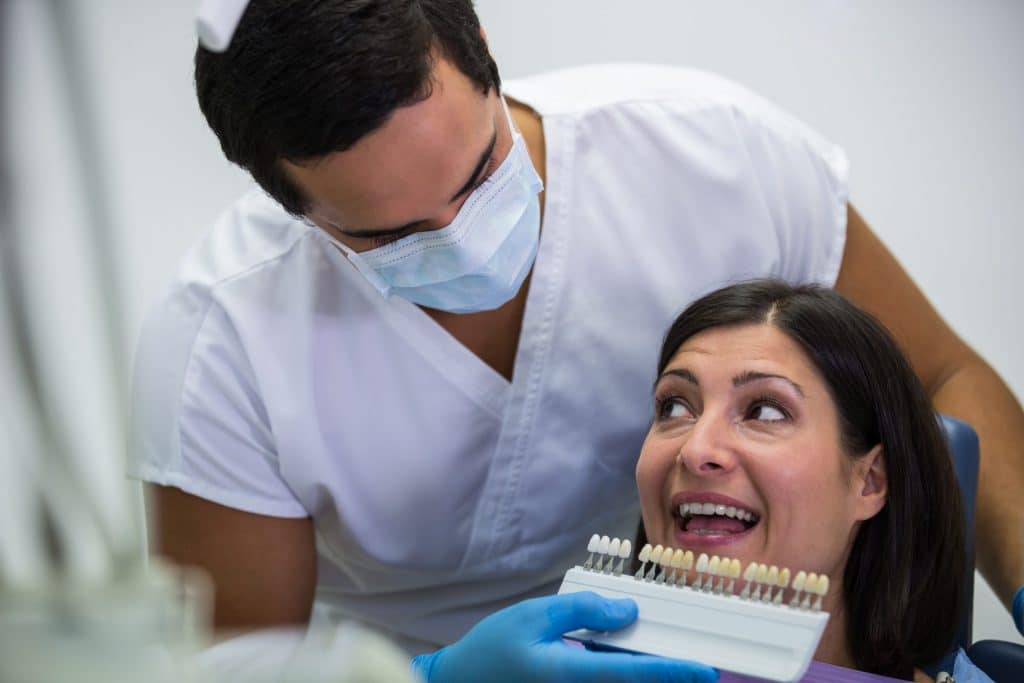 Dentist examining a female patient's teeth shade