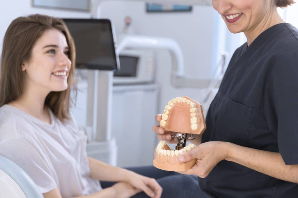 Dentist showing a teeth model to a smiling patient