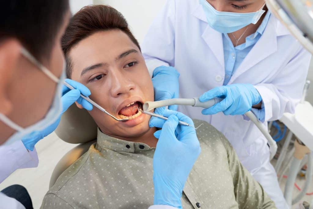 Dentist examining a male patient's teeth
