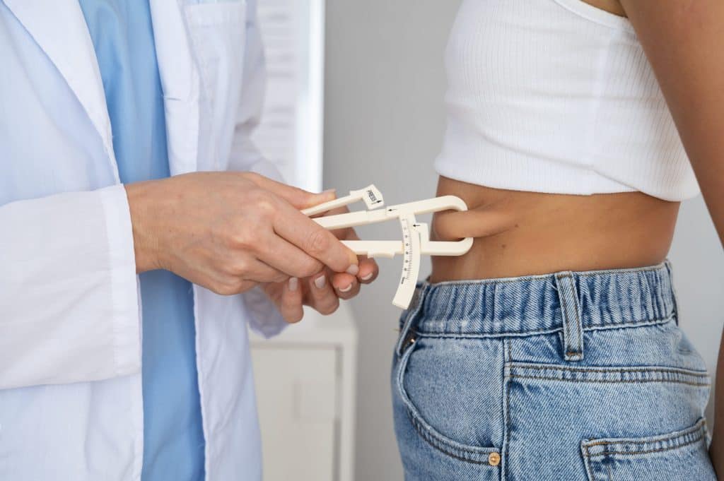 Hands using skinfold calipers to measure body fat