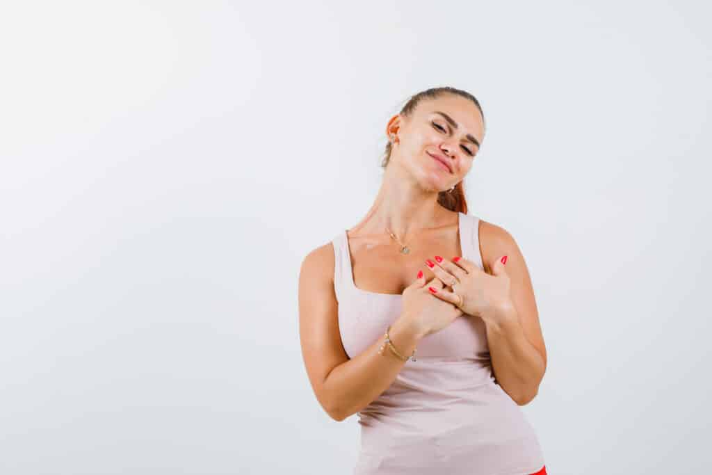 Young woman in singlet, hands on chest, confident pose 2